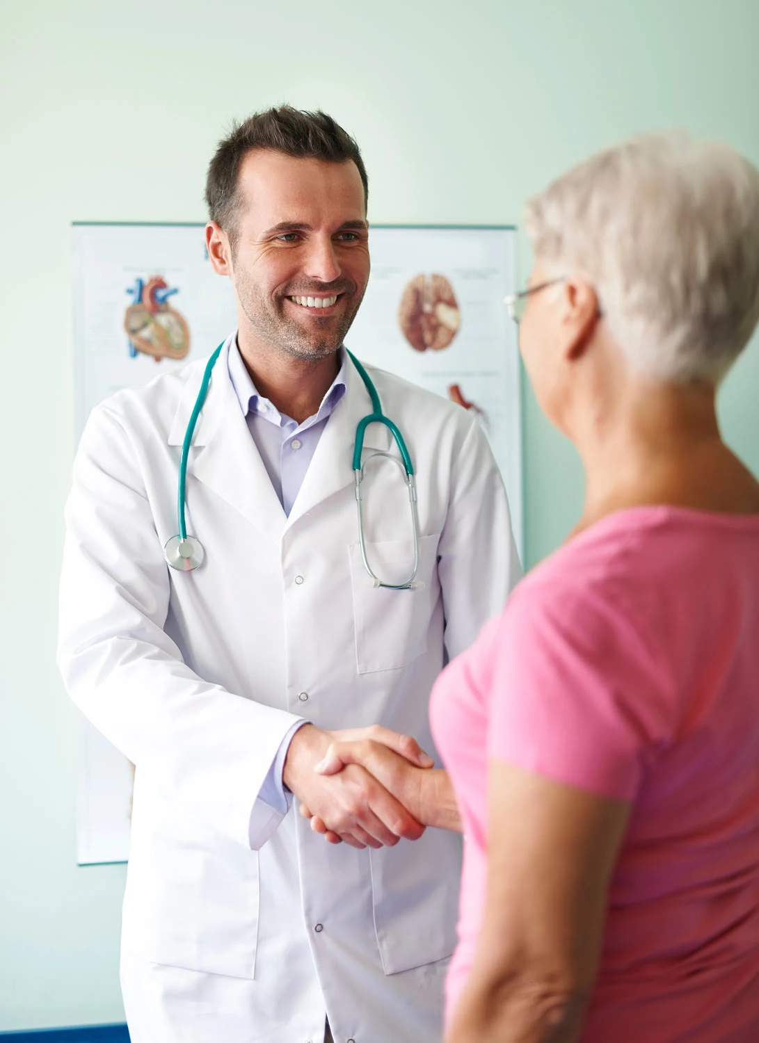 Doctor smiling and holding hand with older woman